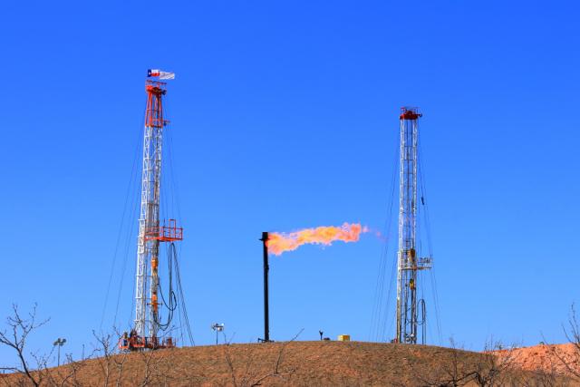 Natural gas flares between two rigs in a West Texas oil field. (Source: GB Hart/Shutterstock.com)