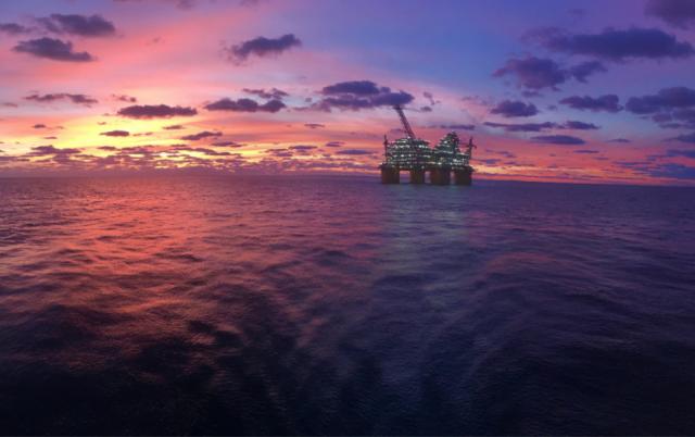 An oil production platform is shown at sunset in the Gulf of Mexico. (Source: revy252/Shutterstock.com)