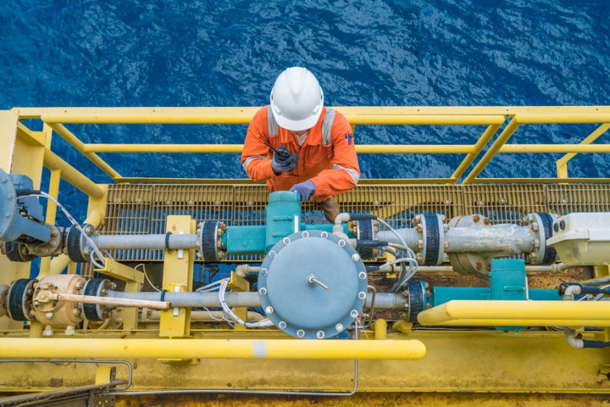 An offshore rig worker checks a meter. (Source: Shutterstock.com)